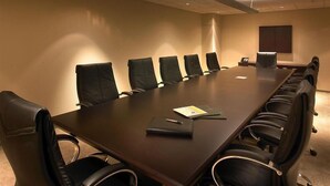 A conference room with a long table, six chairs, and a projector screen. - Churchill Suites Miami Brickell (Miami)