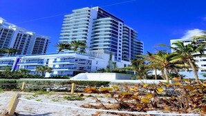 A high-rise hotel with multiple balconies, surrounded by palm trees and other greenery. - Churchill Suites Miami Brickell (Miami)