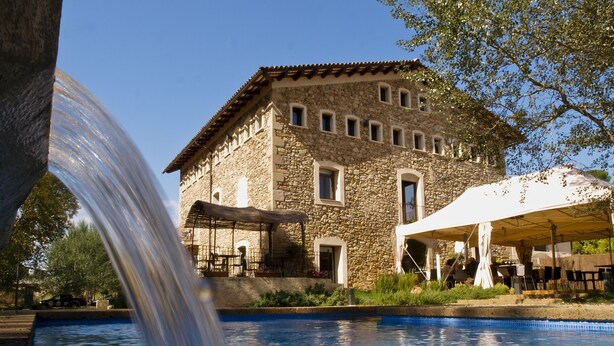 Un edificio de piedra con piscina y cascada.