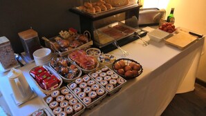 Una mesa de buffet con diversos alimentos, incluyendo pasteles, pan y salsas.