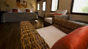 Una habitación con dos camas, mobiliario de mimbre y un ventanal grande.