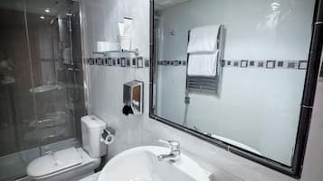 Un baño moderno con ducha de vidrio, lavabo doble y espejo grande.