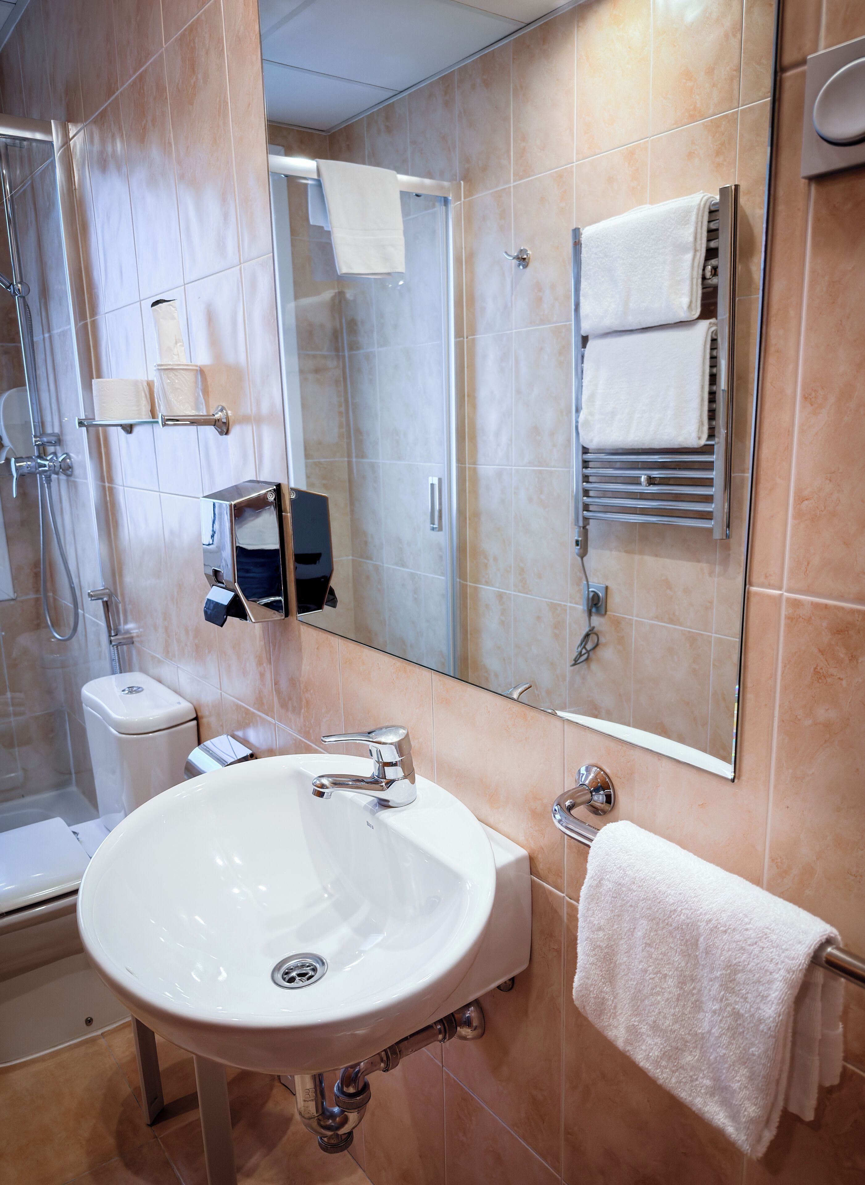Un bany modern amb un rentapeus blanc, una cabina de dutxa de vidre i un mirall gran.
