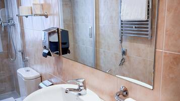 Un bany modern amb un rentapeus blanc, una cabina de dutxa de vidre i un mirall gran.