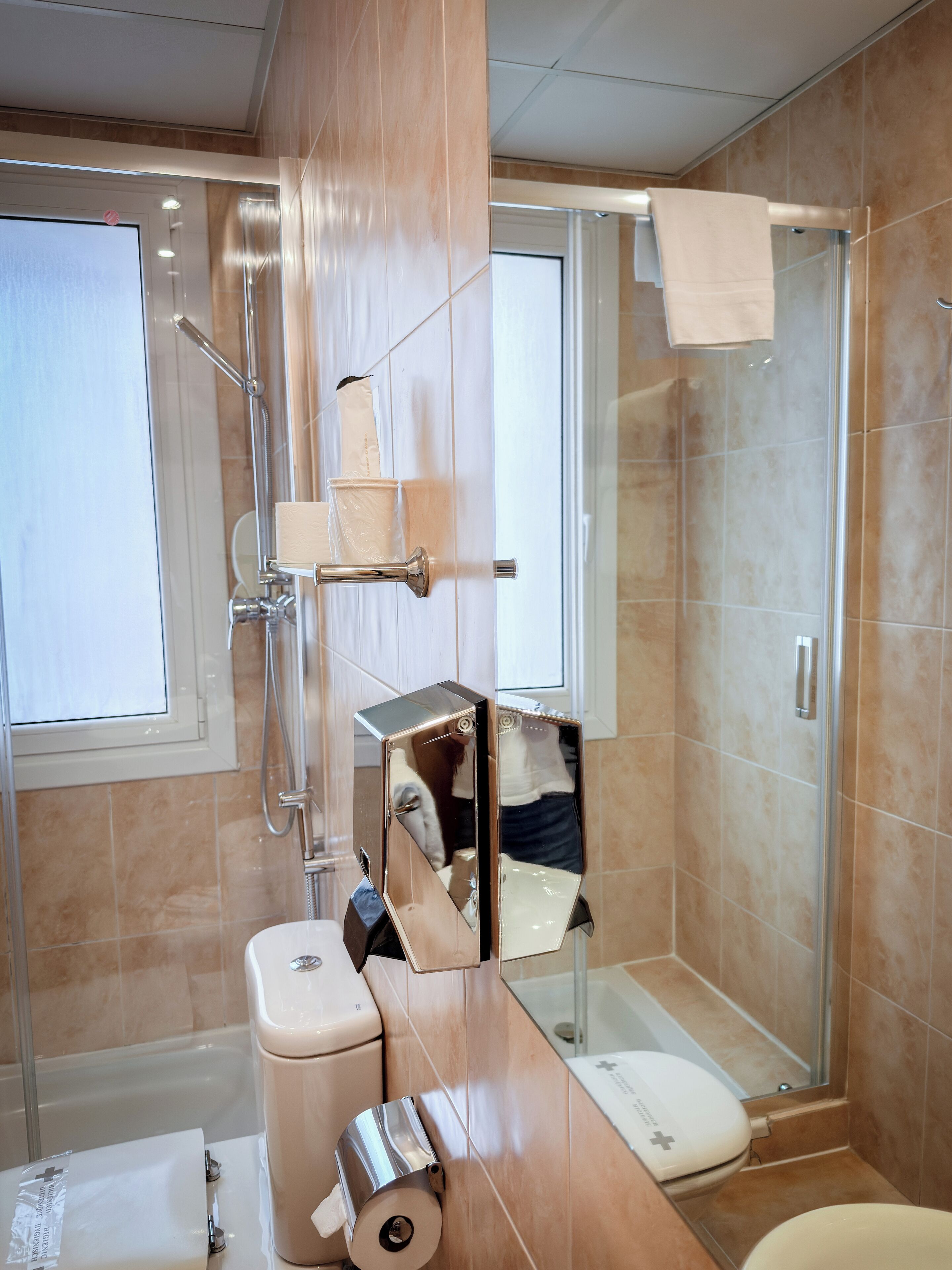 Un baño moderno con cabina de ducha de vidrio, inodoro y lavamanos con toallero.