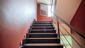Een trap met granieten treden en metalen leuningen, die uitkomt op een plateau met een glazen balustrade.