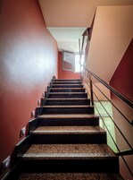 A staircase with granite steps and metal railings, leading to a landing with a glass railing.