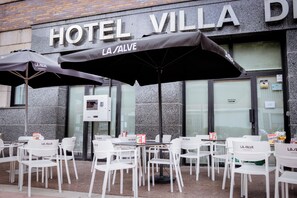An outdoor seating area with tables and chairs in front of a building with a sign reading 'HOTEL VILLA DE LA SALVE.' - Hotel Villa de Ermua (Ermua)