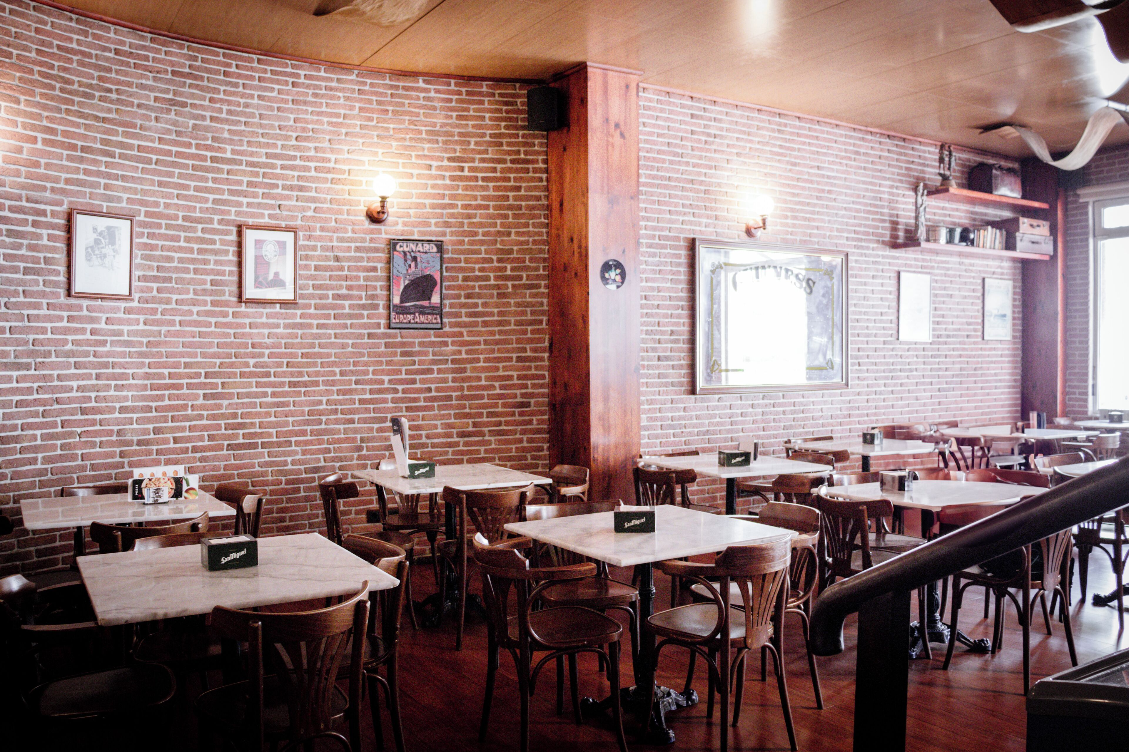 Un restaurante con paredes de ladrillo, mesas y sillas de madera.