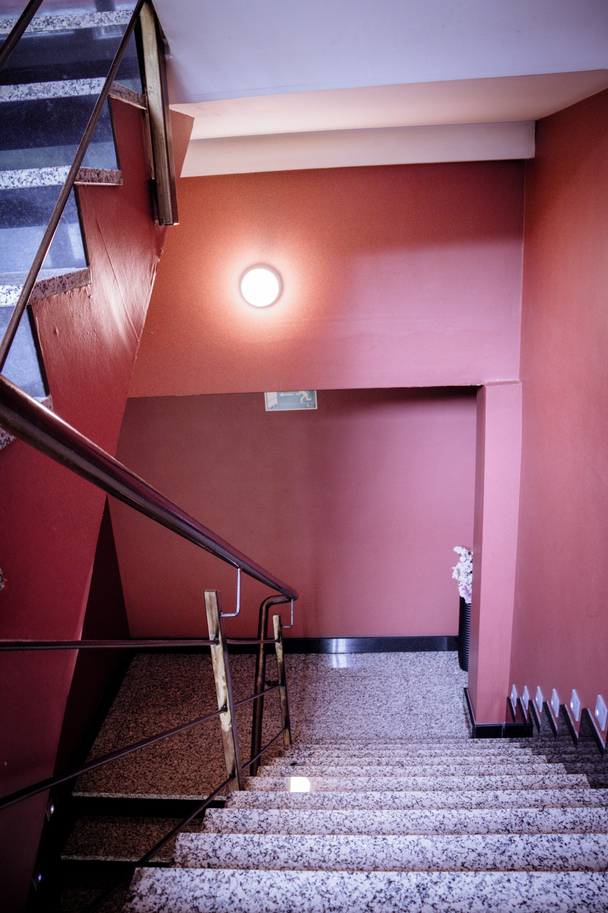 A staircase with metal railings and a red wall.