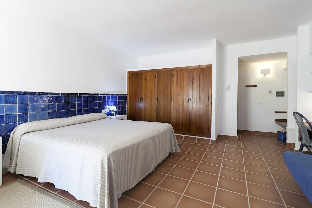 Un dormitorio con una cama, un armario de madera, una mesita de noche y una pared con azulejos azules.