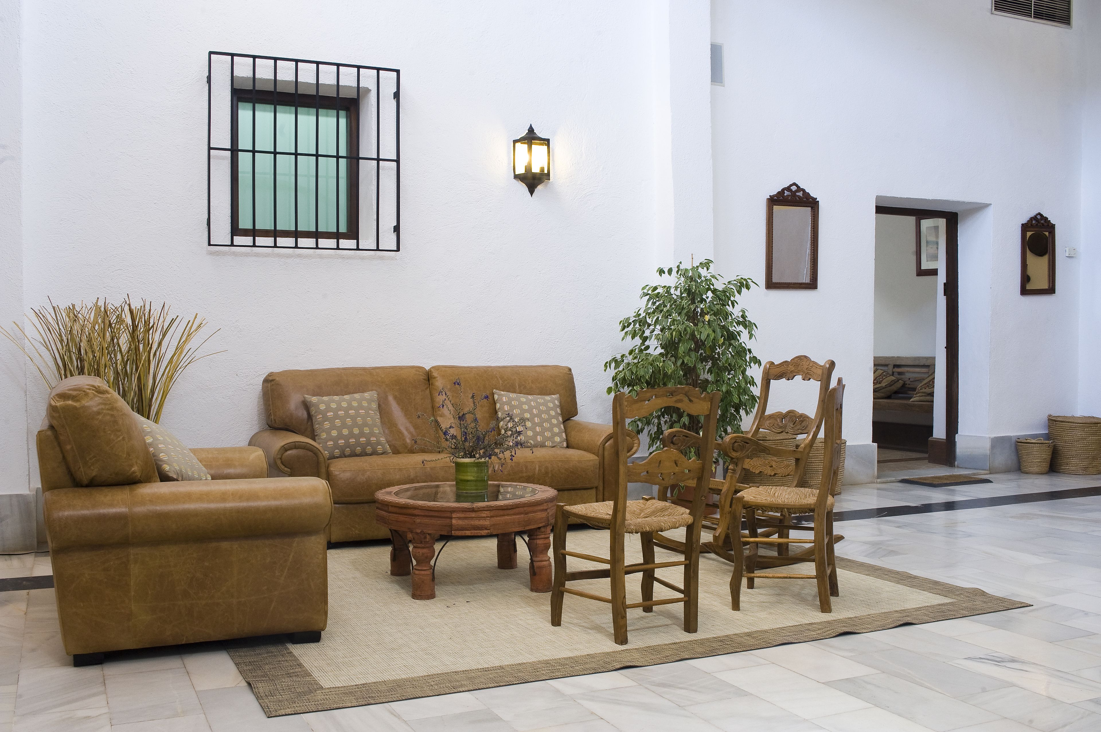 Un hall d’entrée spacieux, avec un ensemble de canapés beige, une chaise en bois, une table basse et une plante en pot.