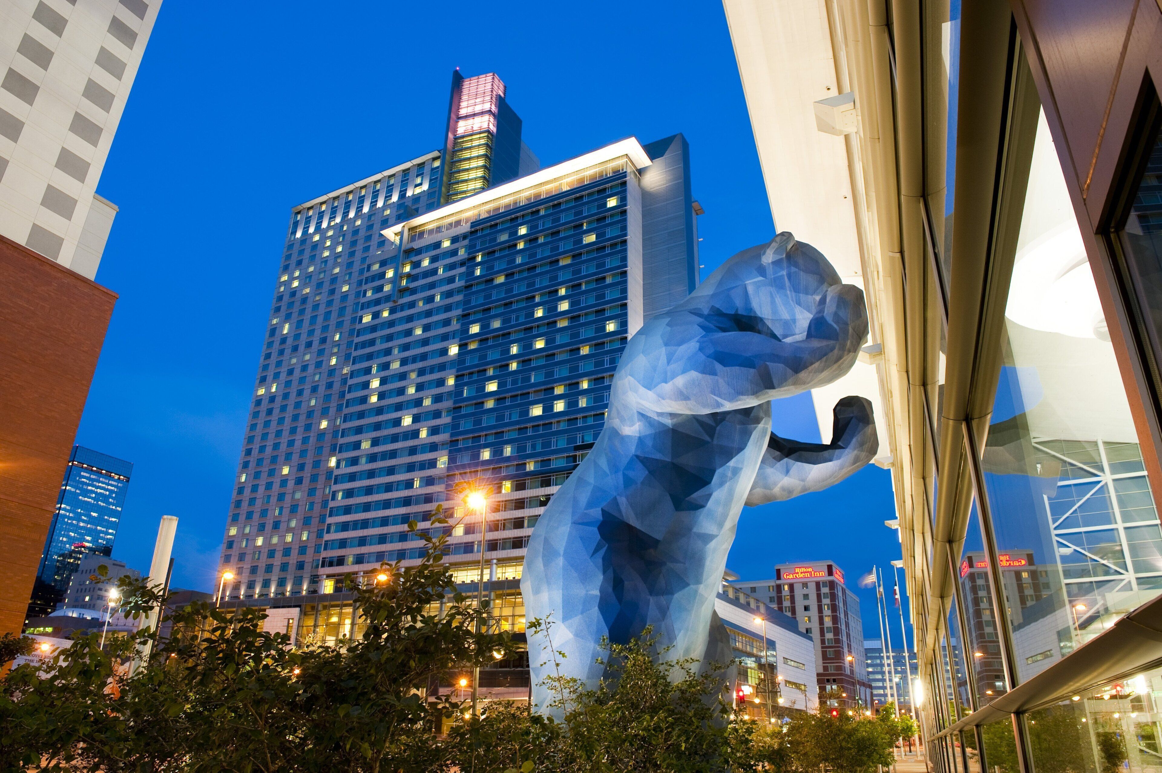 Un moderno edificio hotelero con una fachada de vidrio destacada y una gran escultura en primer plano.