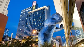 Un moderno edificio hotelero con una fachada de vidrio destacada y una gran escultura en primer plano.