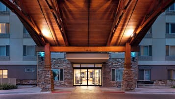 A hotel entrance with a covered walkway, stone pillars, and a glass door entrance.