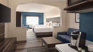 A modern hotel room with a large bed, a sofa, a coffee maker, and a flat-screen TV. - Holiday Inn Express Hotel & Suites Denver Airport by IHG (Denver)