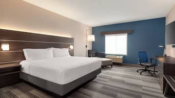 Une chambre d’hôtel avec un grand lit, un bureau, une chaise et une fenêtre.