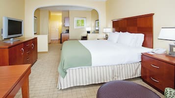 A hotel room with a bed, a desk, a television, a bathroom, and a kitchen area.