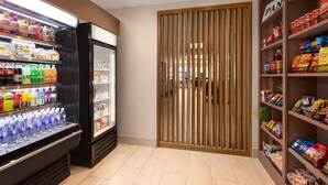 Un expositor refrigerado para bebidas, una despensa con bocadillos y una división de madera.
