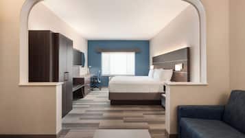 Una habitación de hotel con cama, escritorio, silla, televisión y sofá.