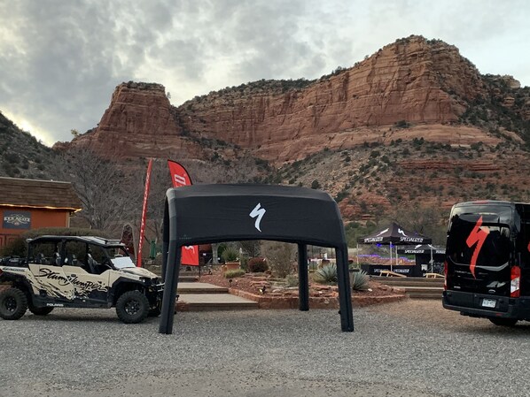 A rugged outdoor area with a large rock formation in the background, a black chair in the foreground, and two off-road vehicles parked nearby. - Red Agave Resort (Sedona)