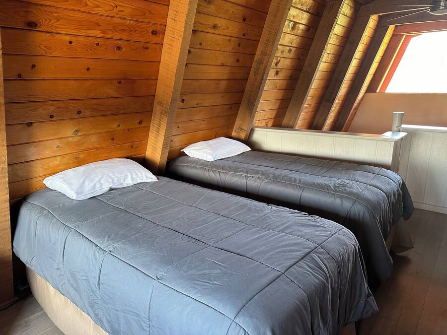 Ein Zimmer mit zwei Betten, Holzwänden und einem Fenster.