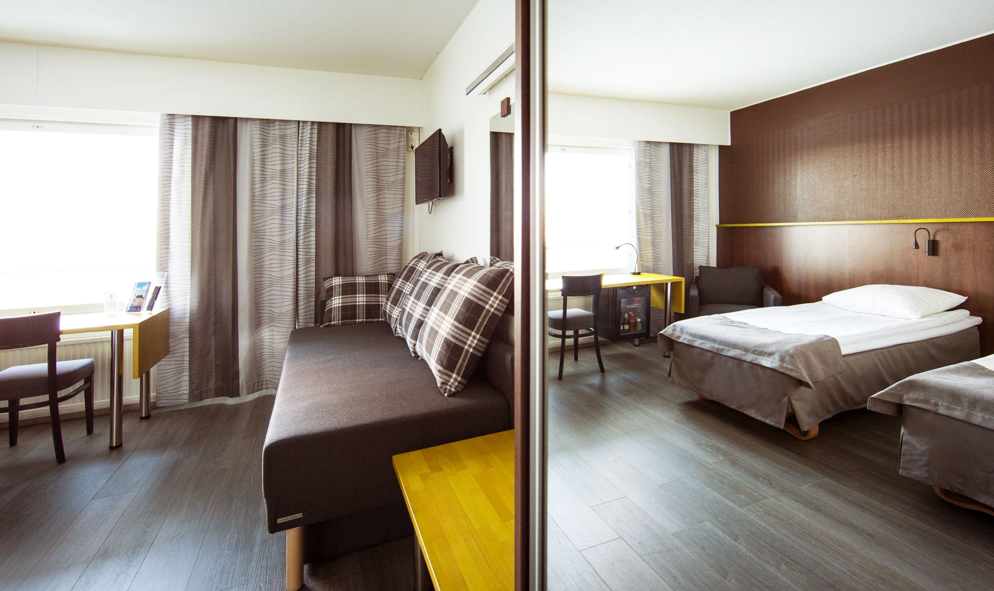 A hotel room with a bed, a sofa, a desk, and a chair.