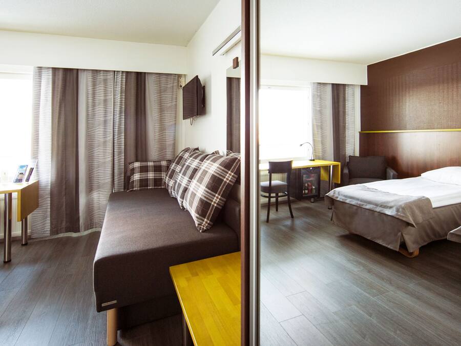 A hotel room with a bed, a sofa, a desk, and a chair.