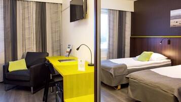 Una habitación de hotel con escritorio, dos camas, televisor y cortinas.