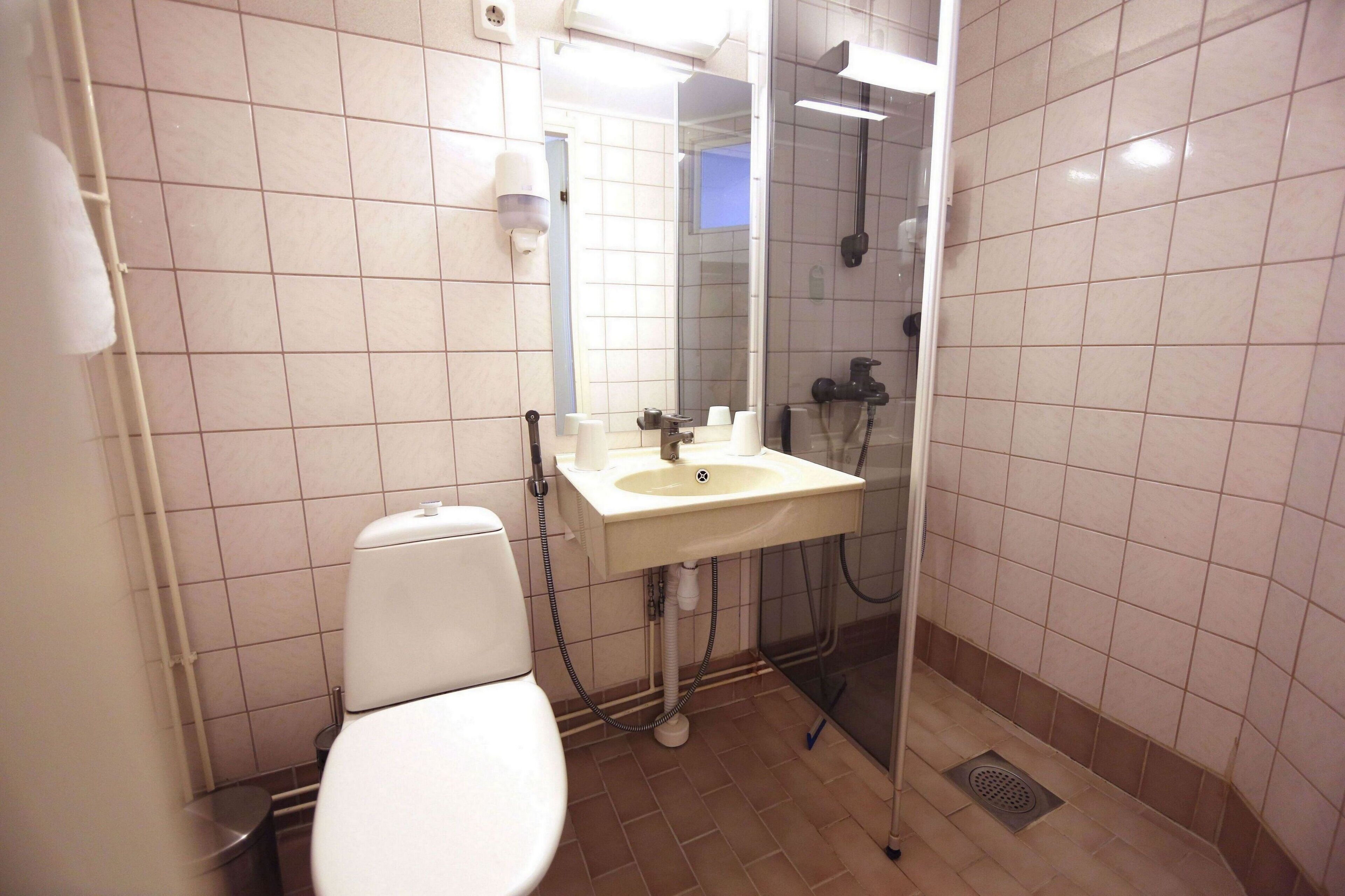 A bathroom with a toilet, sink, and shower.