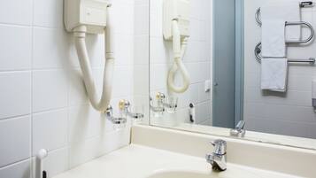 A bathroom with a white sink, a mirror, and a towel rack.