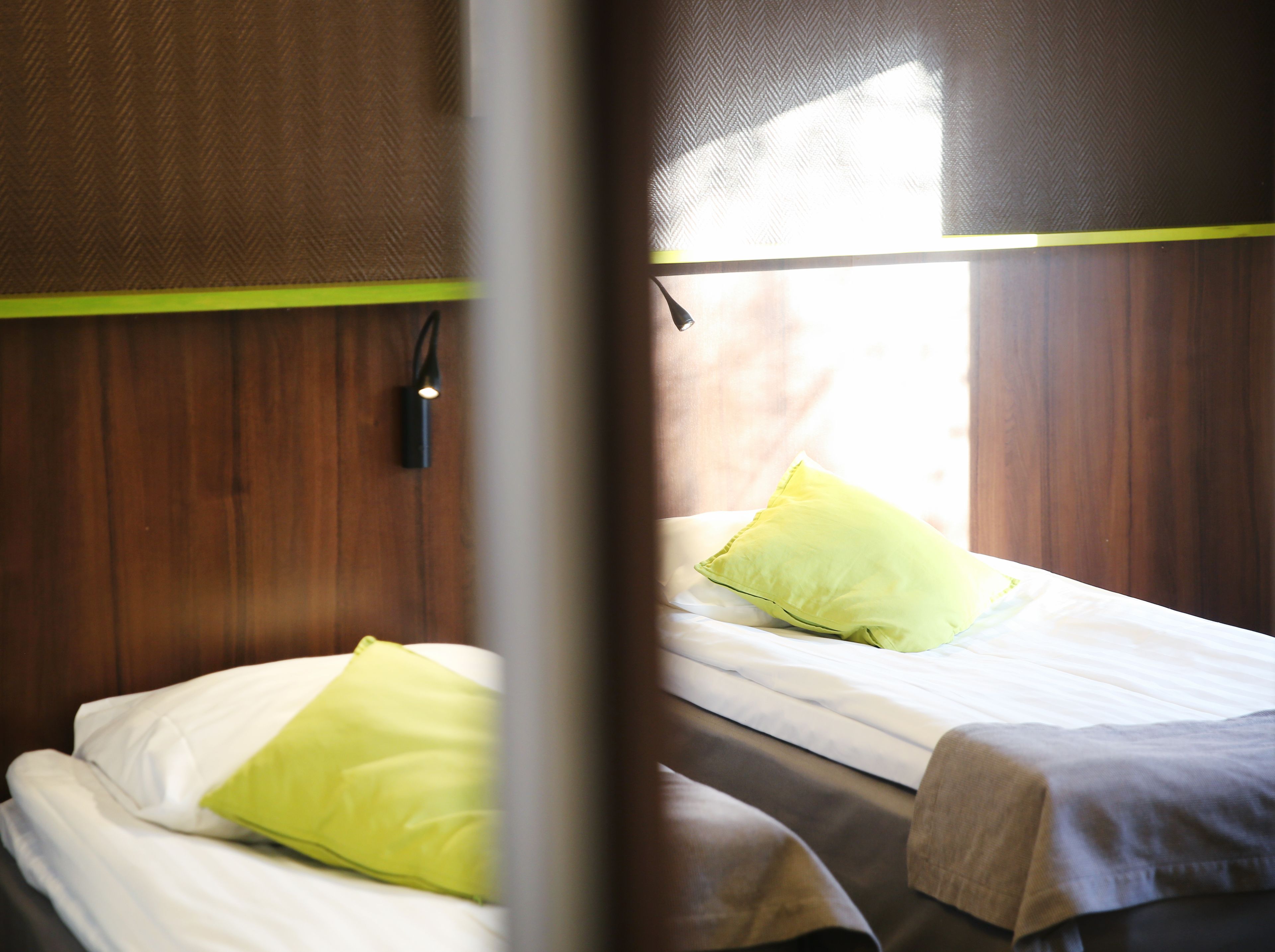 A room with two beds, wooden walls, and a window.