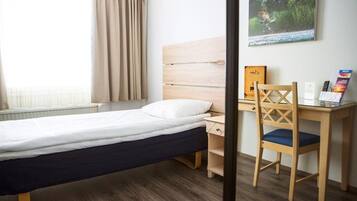 A hotel room with a bed, a desk, a chair, and a window with curtains.