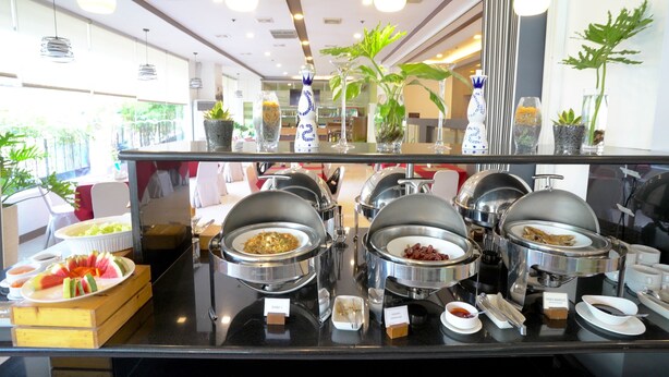 A buffet with various food items and a glass display case. - Alpa City Suites (Mandaue)