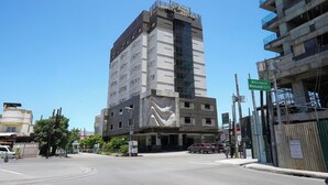 A multi-story hotel with a modern design, featuring a prominent entrance and a large glass facade. - Alpa City Suites (Mandaue)