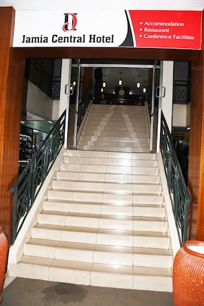 A staircase leading to a hotel interior with a sign indicating accommodation, restaurant, and conference facilities. - Jamia Central Hotel (Nairobi)