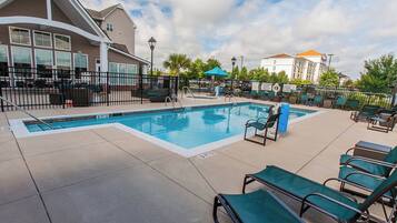 Una piscina al aire libre, sombrillas, sillones reclinables de piscina