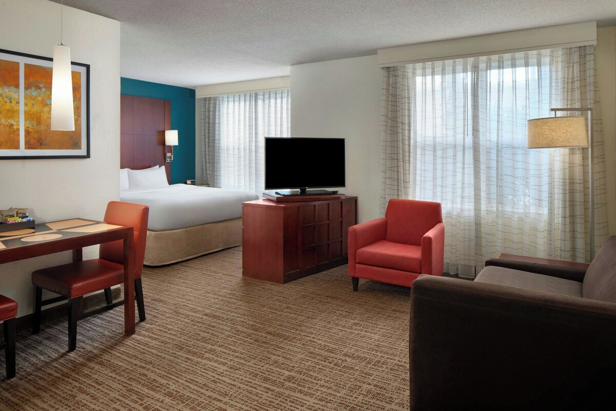 A hotel room with a bed, a TV, a desk, and a chair.