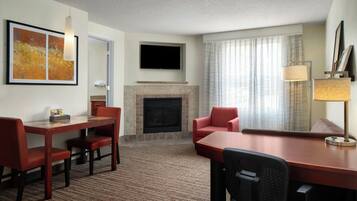 Une chambre d’hôtel dotée d’une cheminée, d’un téléviseur à écran plat fixé au-dessus, d’un coin repas avec une table et des chaises, et d’un canapé.