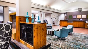 Un moderno vestíbulo de hotel con chimenea, zona de estar y mostrador de recepción.