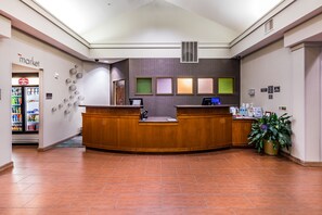 A reception area with a wooden reception desk, a computer, and a plant.