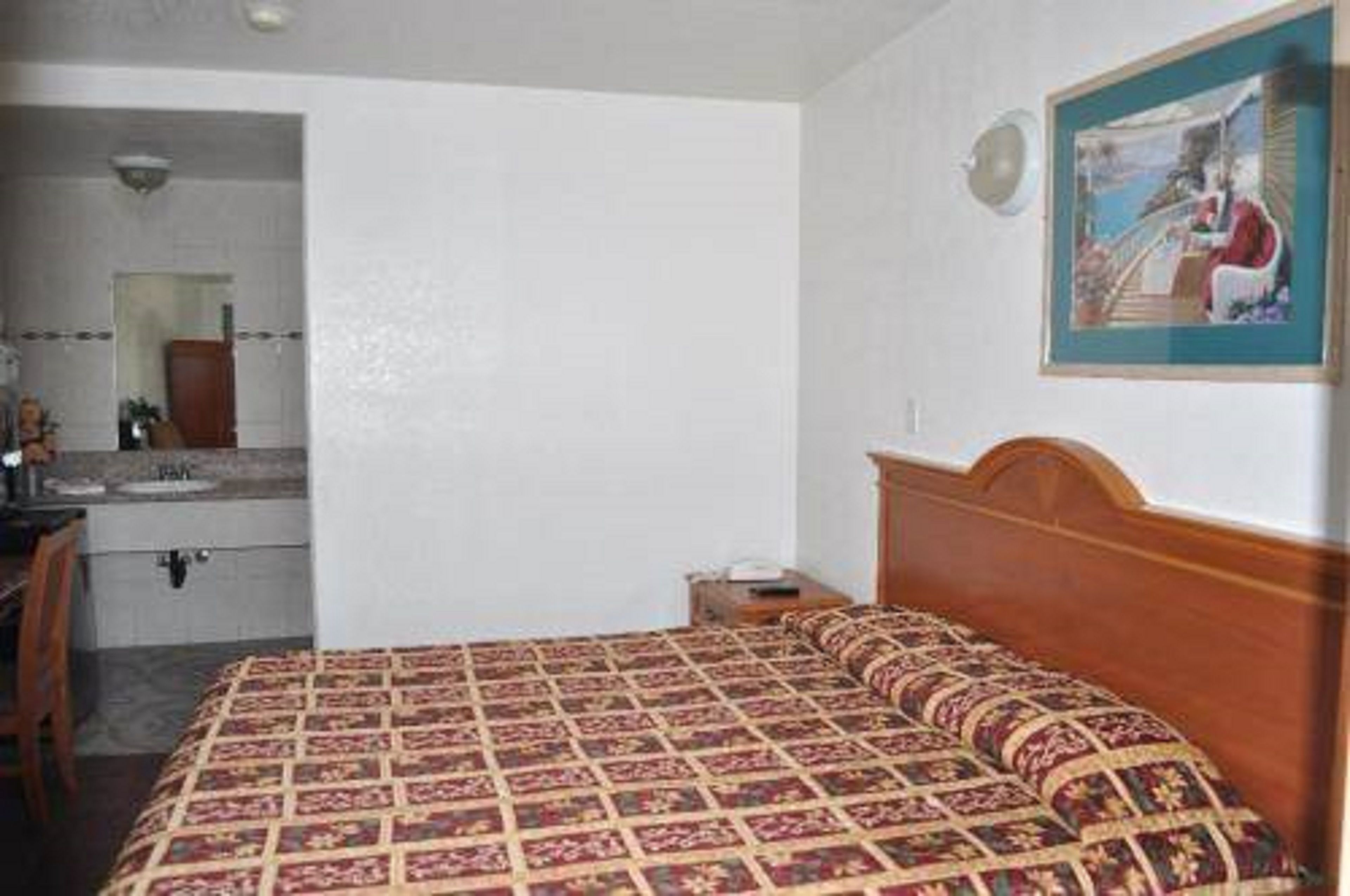 Une chambre à coucher avec un lit, une table de chevet, un miroir et un tableau accroché au mur.