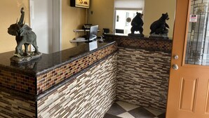 A reception area with a counter, a telephone, a computer, and two bear statues. - Palace Inn Oxnard (Oxnard)