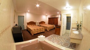 A hotel room with two beds, a bathroom with a sink and mirror, and a small desk. - Palace Inn Oxnard (Oxnard)