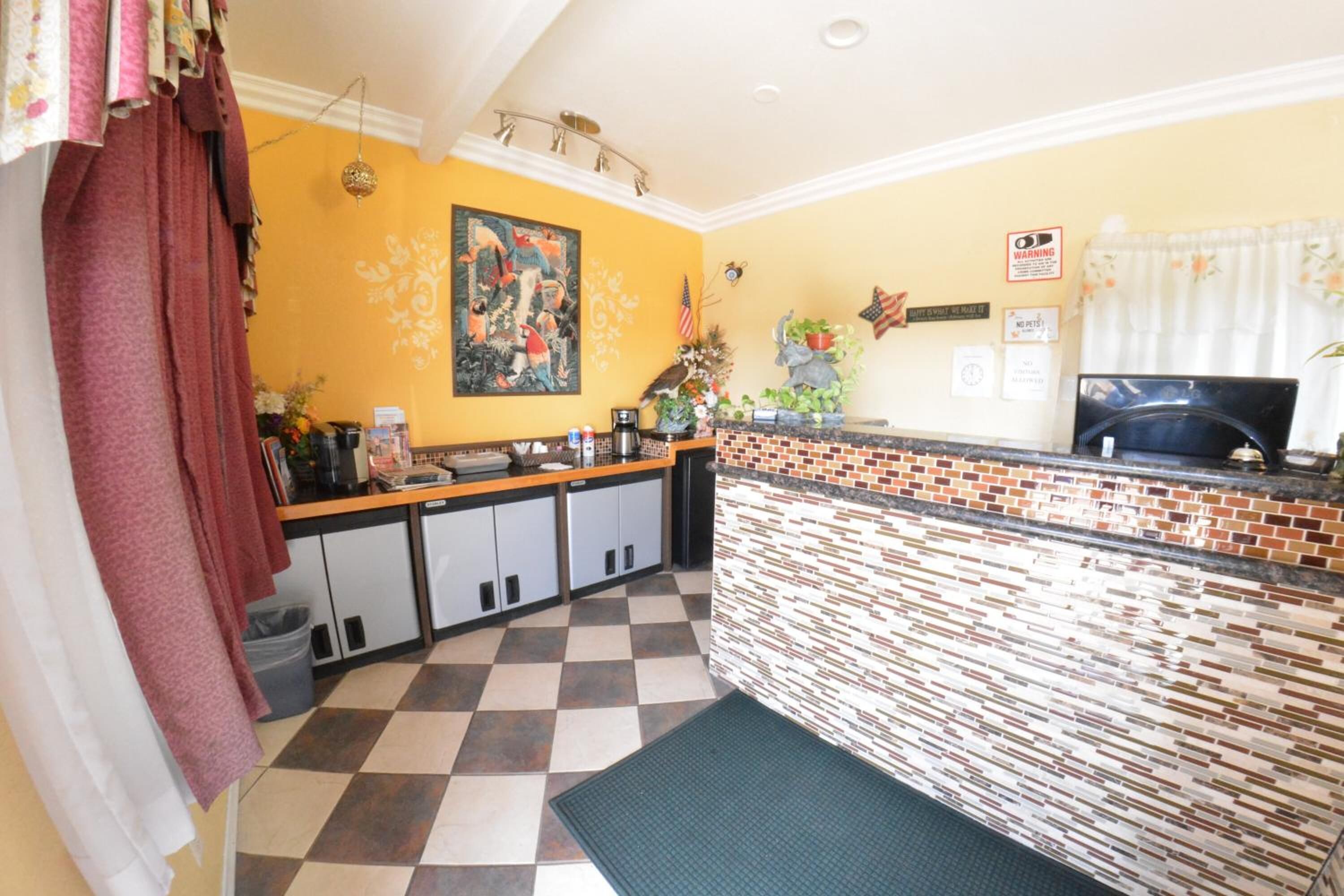 A kitchen with a checkered floor, a brick backsplash, and a painting on the wall.