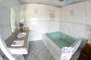 A bathroom with a sink, mirror, and a large bathtub. - Palace Inn Oxnard (Oxnard)