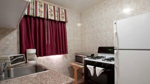 A kitchen with a gas stove, a refrigerator, a microwave, and a coffee maker. - Palace Inn Oxnard (Oxnard)