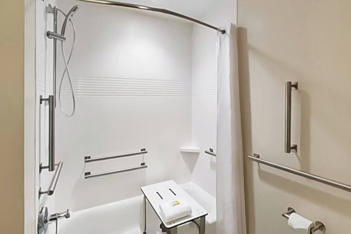 Een moderne badkamer met een inloopdouche, handgrepen, een handdoekrek en een toiletrolhouder.