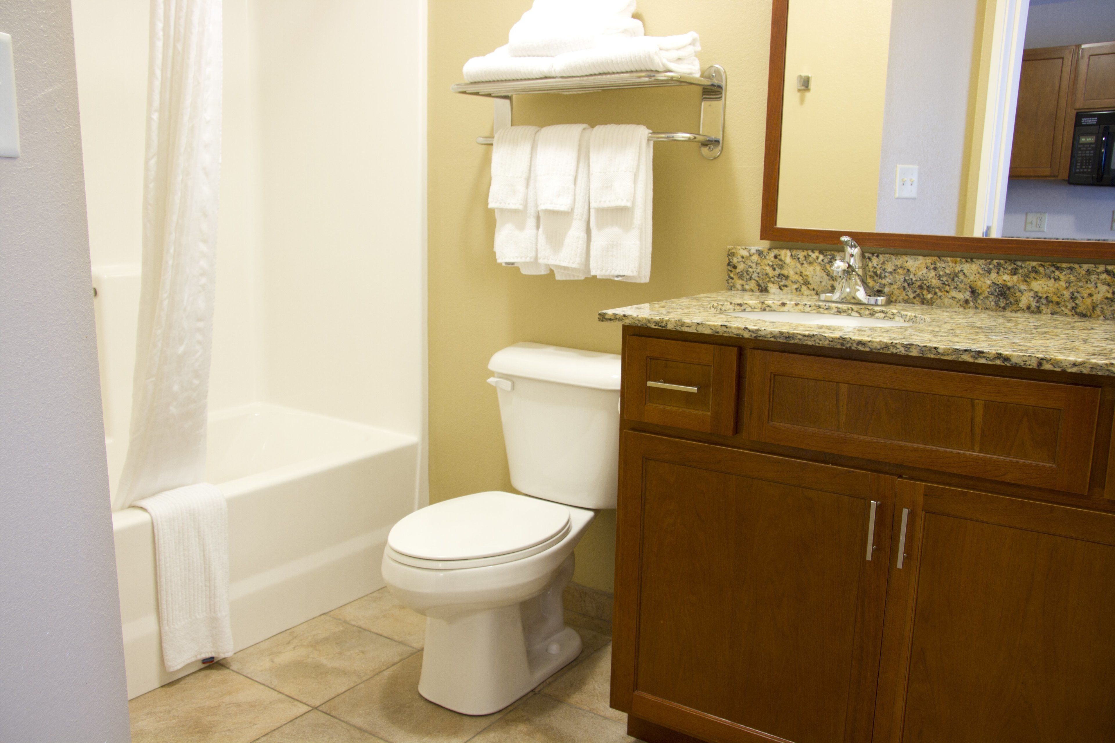 A bathroom with a bathtub, toilet, and wooden cabinets.