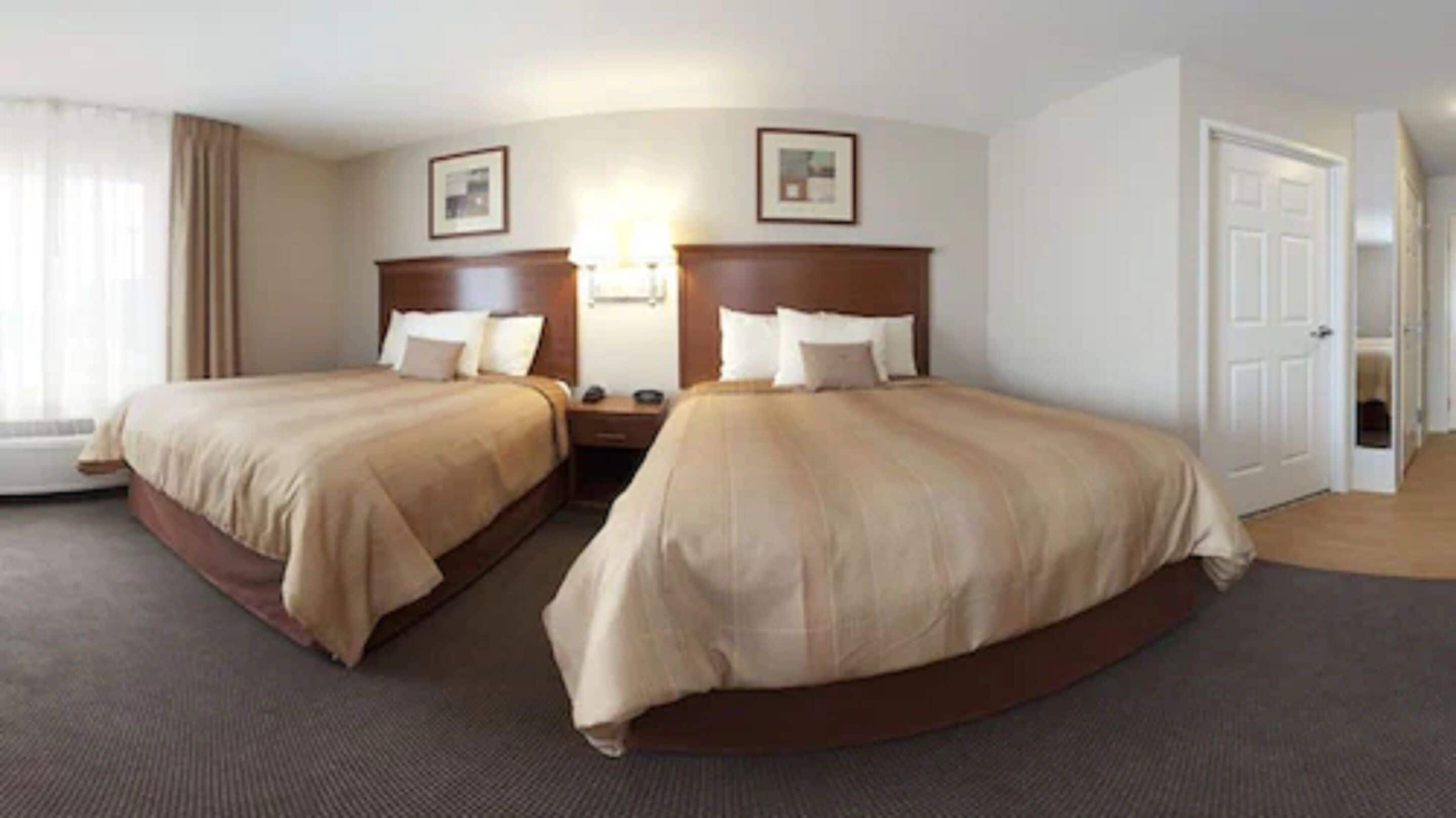 Una habitación de hotel con dos camas, una mesita de noche, una lámpara y una puerta.